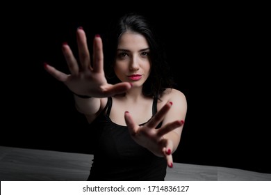 Young Woman Reaching Out With Her Hand To Camera. Portrait Of Woman  On Black Background