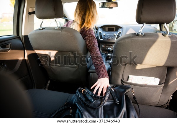 Young\
woman reaching purse from back seat - rear\
view