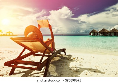 Young woman reading a book at the beach - Powered by Shutterstock