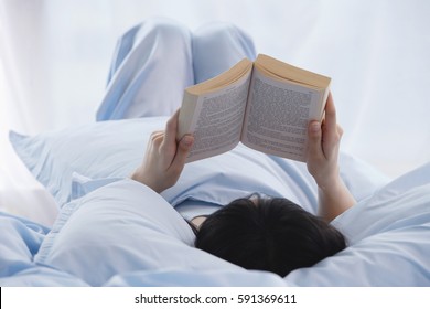 Young Woman Reading A Book In Bed