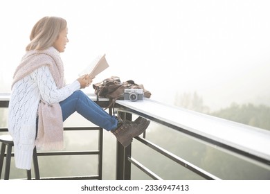 young woman reading book or bible near window and looking mountain view at countryside homestay in the morning sunrise with copy space. journey, trip and relaxing concept. coats blankets in winter. - Powered by Shutterstock