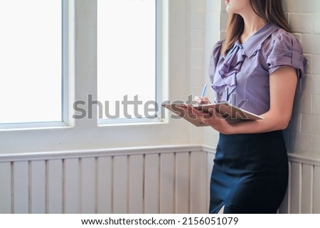 young woman reading a book by the window of her office in the morning to learn and understand the lessons in the book with intention. Ideas for reading lessons in a book to learn by understanding.