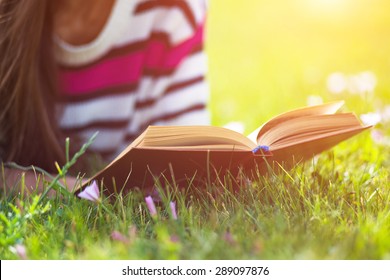 Young Woman Reading Book In City Park At Summer Day