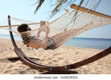 Young woman reading book in hammock on beach - Shutterstock ID 1534539353