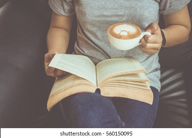 Young Woman Reading A Book And Holding Cup Of Coffee