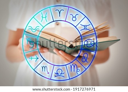 Young woman reading book and illustration of zodiac wheel with astrological signs on light background 