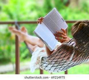 Young Woman Reading A Book Lying In Hammock