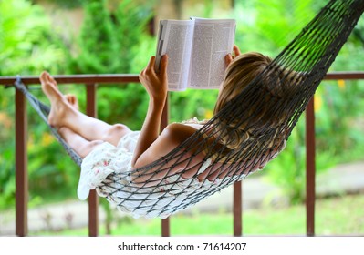 Young woman reading a book lying in a hammock - Powered by Shutterstock