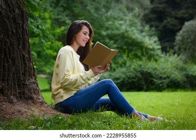 Young woman reading book near tree in park - Powered by Shutterstock