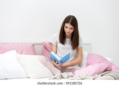 Young Woman Reading Book On Bed At Home