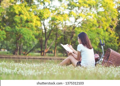Junge Frau, die im Park ein Buch liest