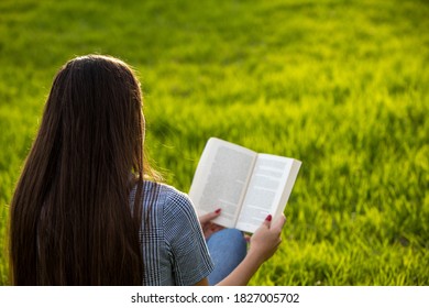 Joven leyendo un libro en el parque