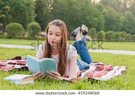 Young Woman Reading Book at Park Lying on Grass