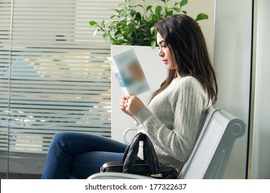  young woman reading brochure in doctor's waiting room