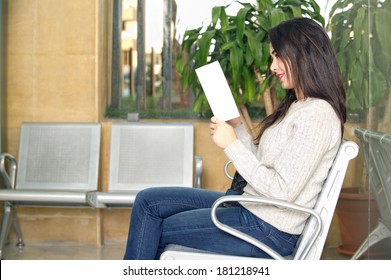 Young Woman Reading Brochure In Doctor's Waiting Room 