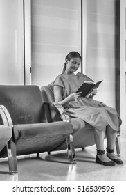 Young Woman Reading Brochure In Doctor's Waiting Room.