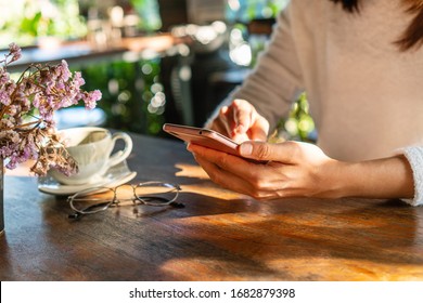 Young woman reading good news on mobile phone during rest in coffee shop, happy Asian female watching her photo on smart phone while relaxing in cafe during free time. - Shutterstock ID 1682879398
