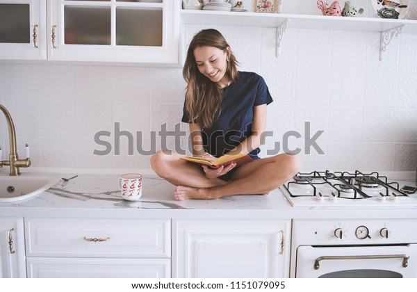 Foto Stok Young Woman Reading Interesting Book Kitchen (Edit Sekarang) 1151...