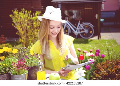 Young Woman Reading Magazine In The Garden