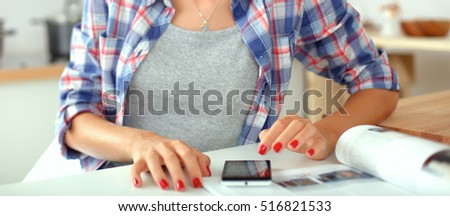 Young woman reading magazine In kitchen at home