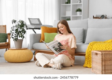 Young woman reading magazine on carpet near sofa at home - Powered by Shutterstock