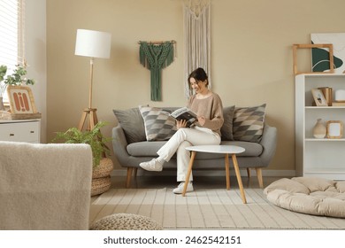 Young woman reading magazine on sofa with hanging wall tapestries in living room - Powered by Shutterstock