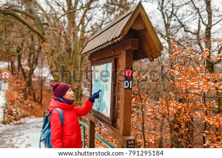 Young woman reading map while traveling in snowy autumn forest in national park