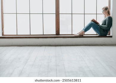 Young woman reading near huge window - Powered by Shutterstock