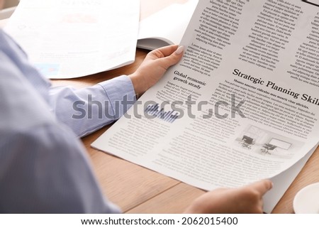 Young woman reading newspaper in office, closeup