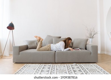 Young Woman Reading On The Couch At Home.