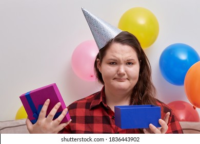 A Young Woman Received A Bad Birthday Present In A Bright Box. Balloons In The Background.