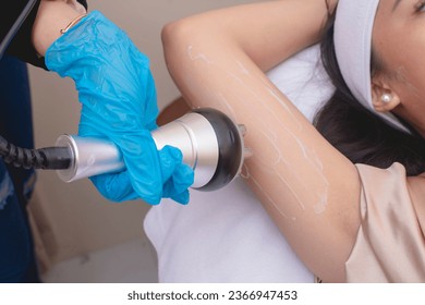 A young woman receives a radiofrequency upper arm skin tightening or slimming treatment. At a facial care, dermatologist or aesthetic clinic.