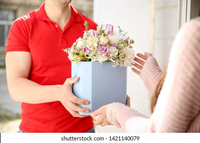 Young Woman Receiving Beautiful Flowers From Delivery Man At Home