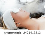 Young woman receiving beauty treatment with thermal ozone facial steamer. Professional cosmetology salon or spa procedure.