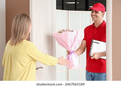 Young woman receiving bouquet of roses from courier at door - Powered by Shutterstock