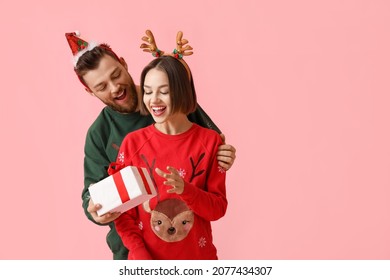 Young woman receiving Christmas gift from her boyfriend on color background - Powered by Shutterstock