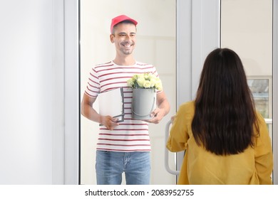 Young Woman Receiving Flowers From Courier At Home