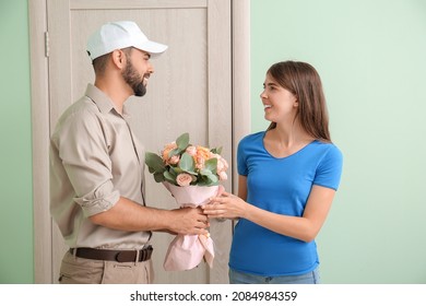 Young Woman Receiving Flowers From Courier At Home