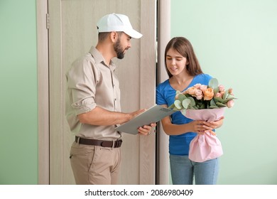 Young Woman Receiving Flowers From Courier At Home