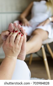 Young Woman Receiving Foot Massage In Spa Salon. Girl Sitting On Chair At Home And Having Massage Legs For Better Circulation.