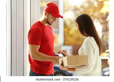 Young Woman Receiving Parcel From Delivery Man