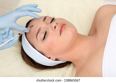 Young woman receiving plastic surgery injection on her face close up