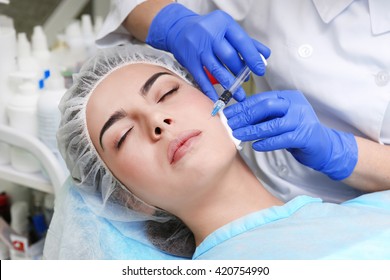 Young woman receiving plastic surgery injection on her face, closeup