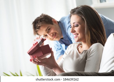 Young Woman Receiving A Surprise Gift Box From Her Boyfriend At Home.