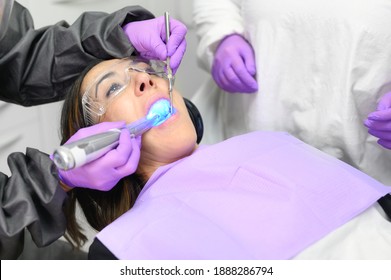 Young Woman Receiving Ultraviolet Light Procedure At Dentist Office. High Quality Photo