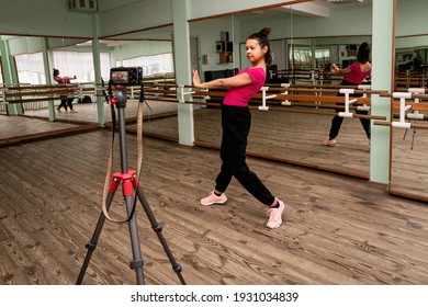 Young Woman Recording On Camera A Dance Lesson In A Choreography Hall With Mirrors. Fitness Trainer Does Exercises.