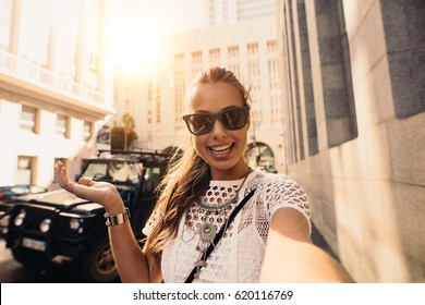 Young Woman Recording A Selfie Video In A Street. Vlogger Recording Content For Her Travel Vlog.