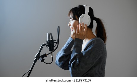 A young woman recording a song.	
