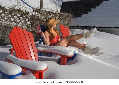 Young Woman in a Red Bathing Suit Sitting on Snow Covered Chairs in the Backyard Holding a Summer Drink During Winter, New Brunswick Canada
