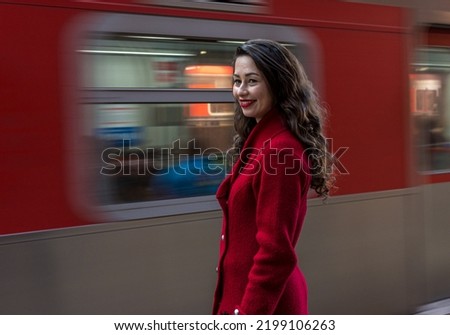 Young woman in red coat at European-style train station and antique on platform and stairs blur areas and objects  panning move